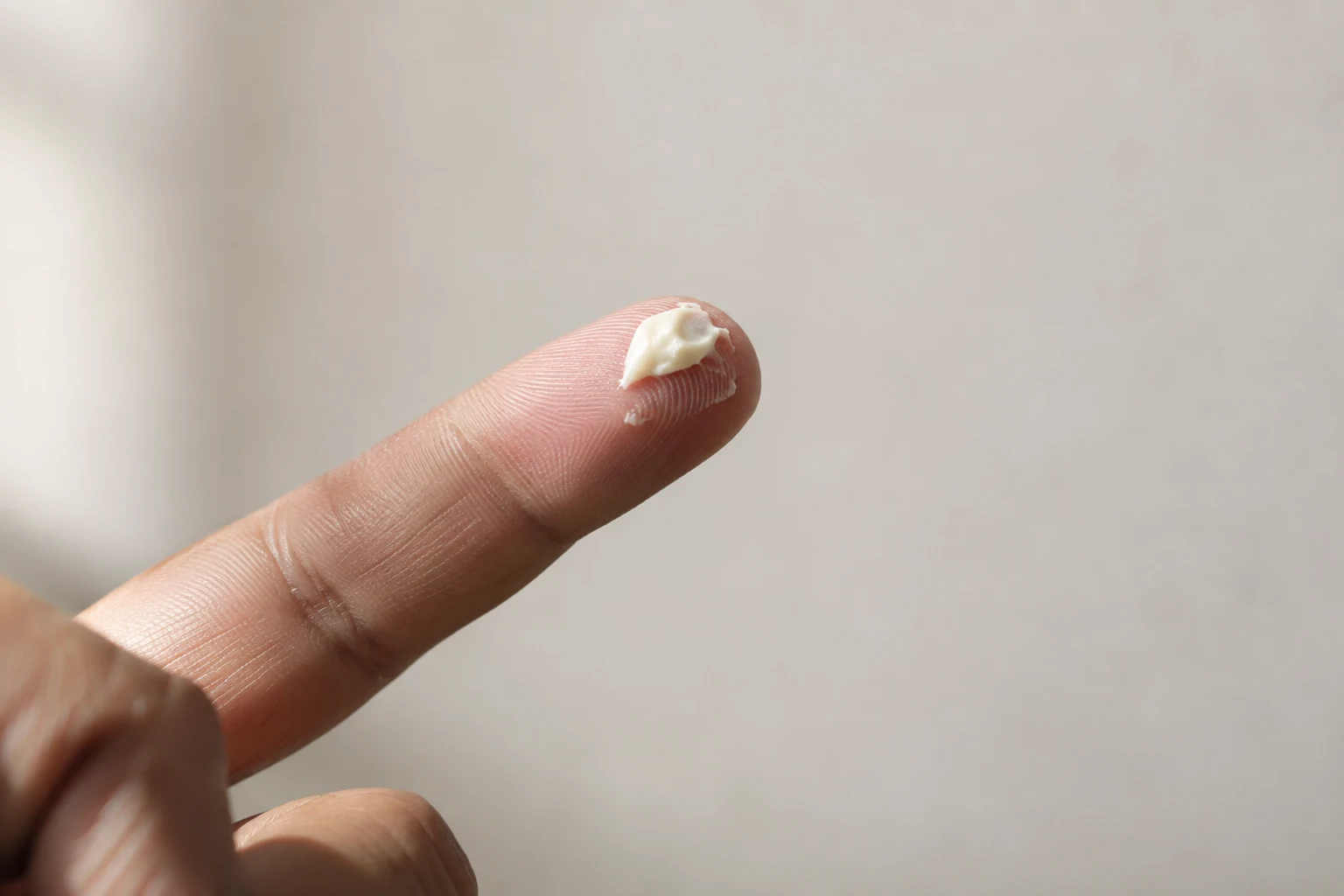 Pequena quantidade de pasta de finalização na ponta de um dedo, com digitais e dobras naturais visíveis.
